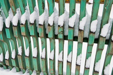 Eski harap olmuş ahşap çitler karla kaplı.