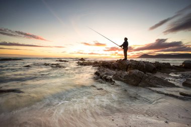 Güney Afrika 'nın Batı Burnu' ndaki Gansbaai dışında kayalıklarda yalnız bir balıkçı.