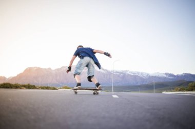 Açık bir yolda kaykaycı serbest stil numaraları yapıyor.