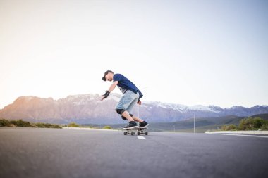 Açık bir yolda kaykaycı serbest stil numaraları yapıyor.