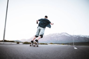 Açık bir yolda kaykaycı serbest stil numaraları yapıyor.