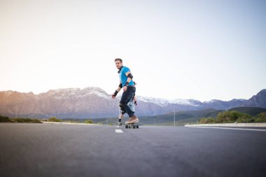 Açık bir yolda kaykaycı serbest stil numaraları yapıyor.