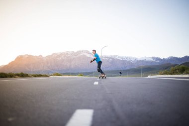 Açık bir yolda kaykaycı serbest stil numaraları yapıyor.