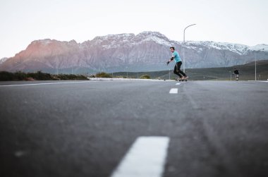 Açık bir yolda kaykaycı serbest stil numaraları yapıyor.