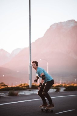 Açık bir yolda kaykaycı serbest stil numaraları yapıyor.