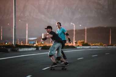 Açık bir yolda kaykaycı serbest stil numaraları yapıyor.