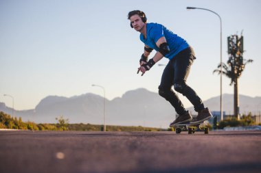 Açık bir yolda kaykaycı serbest stil numaraları yapıyor.