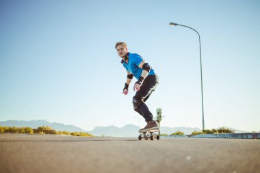 Açık bir yolda kaykaycı serbest stil numaraları yapıyor.