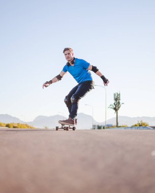 Açık bir yolda kaykaycı serbest stil numaraları yapıyor.