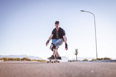 Açık bir yolda kaykaycı serbest stil numaraları yapıyor.