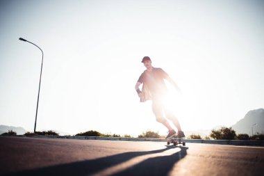 Açık bir yolda kaykaycı serbest stil numaraları yapıyor.