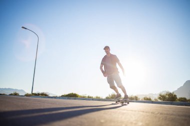 Açık bir yolda kaykaycı serbest stil numaraları yapıyor.