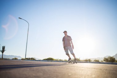 Açık bir yolda kaykaycı serbest stil numaraları yapıyor.