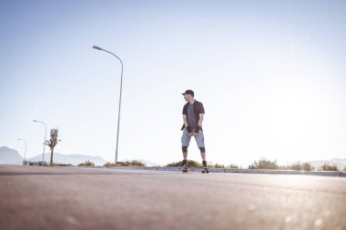 Açık bir yolda kaykaycı serbest stil numaraları yapıyor.