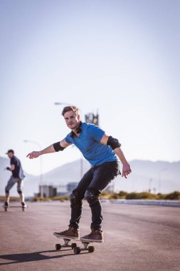 Açık bir yolda kaykaycı serbest stil numaraları yapıyor.