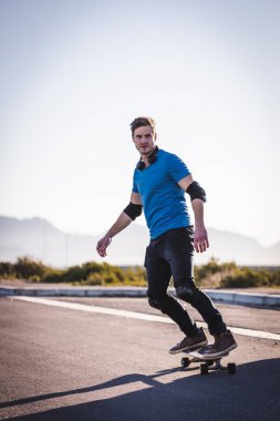 Açık bir yolda kaykaycı serbest stil numaraları yapıyor.