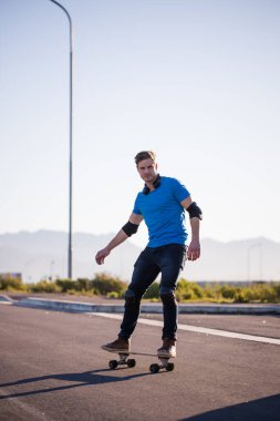 Açık bir yolda kaykaycı serbest stil numaraları yapıyor.