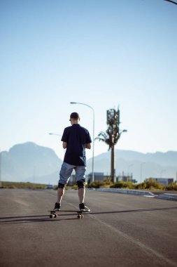 Açık bir yolda kaykaycı serbest stil numaraları yapıyor.