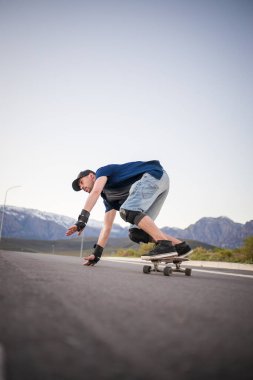 Açık bir yolda kaykaycı serbest stil numaraları yapıyor.