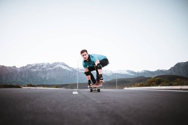 Açık bir yolda kaykaycı serbest stil numaraları yapıyor.