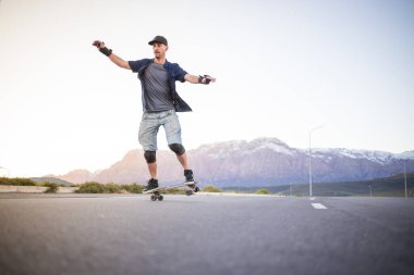 Açık bir yolda kaykaycı serbest stil numaraları yapıyor.