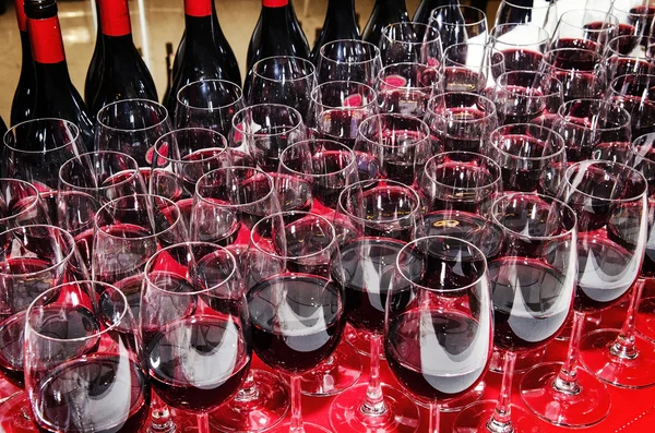 Glasses and bottles of red wine on cocktail party table — Stock Photo, Image