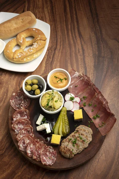 木のテーブルの上で肉やパンとドイツの冷たいカットタパススナックプレート背景 — ストック写真