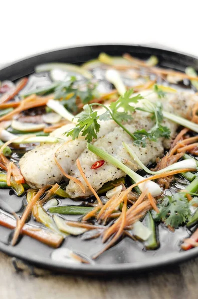 中国の広東風の湯気のある魚の切り身と野菜を熱々の皿に盛り — ストック写真