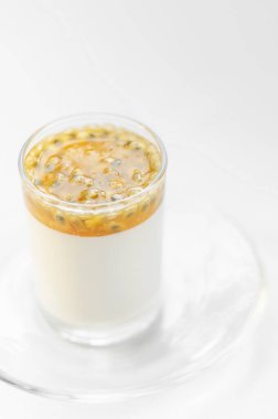 Vejetaryen sütsüz organik hindistan cevizi kremalı panna cotta ve beyaz arka planda tutku meyveli tatlı.