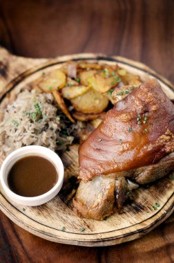 SCHWEINSHAXE Geleneksel Alman domuz boğumları lahana turşusu ve kırsal ahşap arka planda patates bavyerası