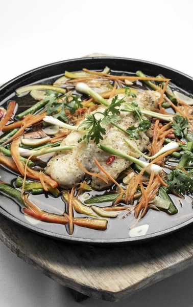 中国の広東風の湯気のある魚の切り身と野菜を熱々の皿に盛り — ストック写真