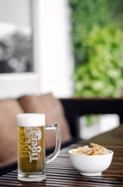 Singapur 'daki açık bar teras masasında bir bardak bira ve Taro cipsi.