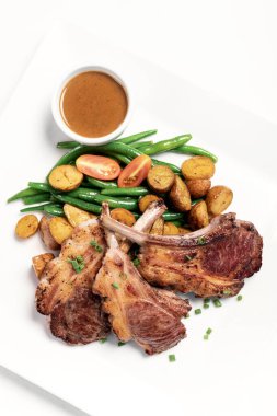 Avustralya organik kuzu pirzolası, sebze ve soslu beyaz arka plan.