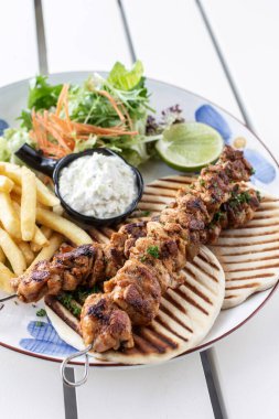 Yunanistan 'da Mykonos restoranındaki beyaz masada tavuk şişi jiroskopu tabağı.