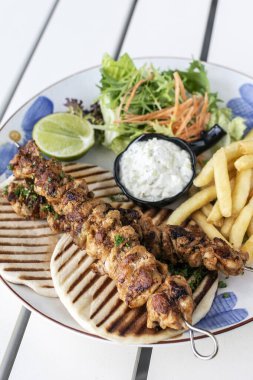 Yunanistan 'da Mykonos restoranındaki beyaz masada tavuk şişi jiroskopu tabağı.