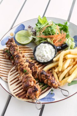 Yunanistan 'da Mykonos restoranındaki beyaz masada tavuk şişi jiroskopu tabağı.