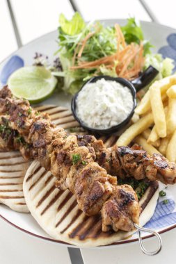 Yunanistan 'da Mykonos restoranındaki beyaz masada tavuk şişi jiroskopu tabağı.