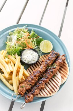 Yunanistan 'da Mykonos restoranındaki beyaz masada tavuk şişi jiroskopu tabağı.