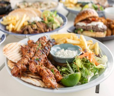 Yunanistan 'da Mykonos restoranındaki beyaz masada tavuk şişi jiroskopu tabağı.