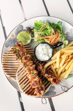 Yunanistan 'da Mykonos restoranındaki beyaz masada tavuk şişi jiroskopu tabağı.