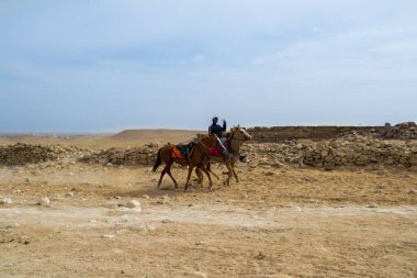 Kahire / Mısır - 09 Şubat 2021: Giza Piramitleri bölgesinde at süren bir atlı. Giza Piramitleri 'nde at binme ve deve binme gelenekleri gelenekseldir..