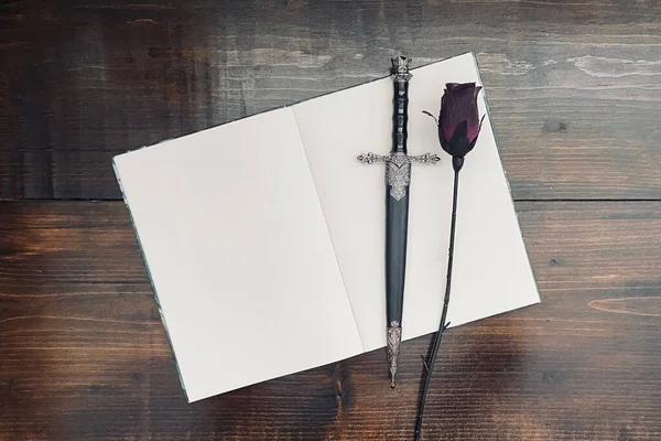 Fantasy image. Black rose. dagger. blank book. flat lay background. Flat lay book.