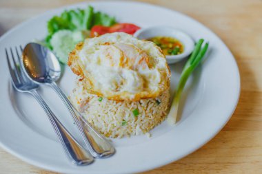 Tahta masadaki beyaz tabakta yumurtalı pilav. 