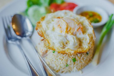 Tahta masadaki beyaz tabakta yumurtalı pilav. 