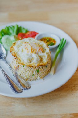 Tahta masadaki beyaz tabakta yumurtalı pilav. 