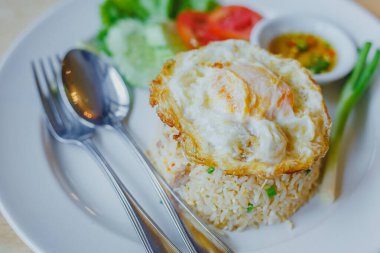 Tahta masadaki beyaz tabakta yumurtalı pilav. 