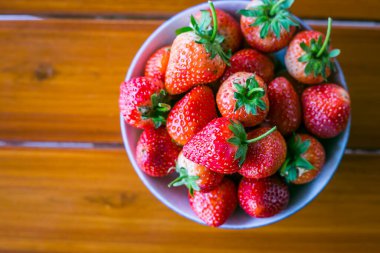 Tahta masadaki kasede sade sahneli taze çilekler.