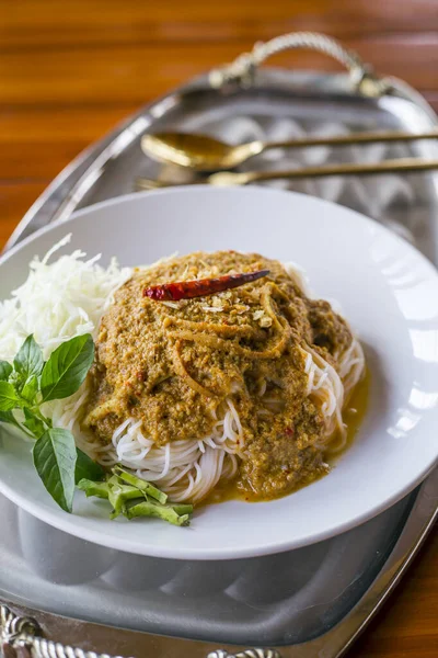 Rice noodles in fish curry sauce with vegetables on the table