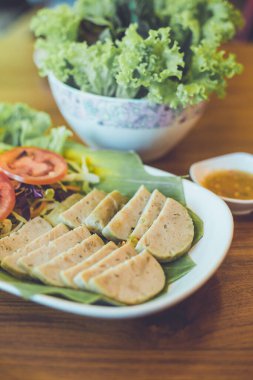 Beyaz bir tabakta acı soslu buğulanmış Vietnam domuz sosisi, seçici bir odak noktası.
