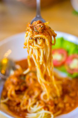 Domates soslu spagetti ve ahşap masada taze fesleğen.